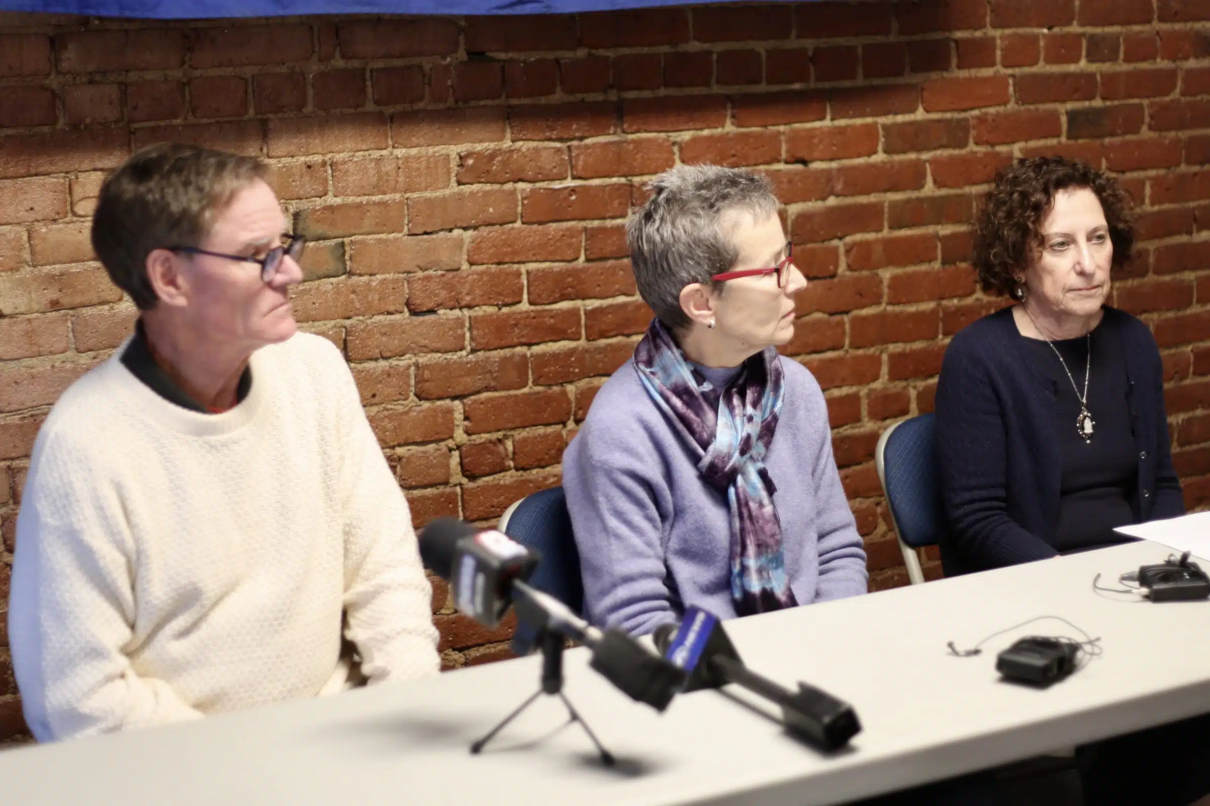 There Rhode Island Attorneys sit at a table in the Rhode Island ACLU press room. Richard Corley, Jennifer Wood from the Rhode Island Center for Justice and Lynette Labinger.